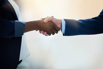 Two people in business attire shaking hands as if a deal has been reached.